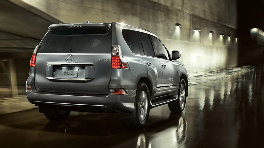 A silver suv parked in the rain on a wet street.