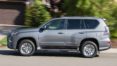 A silver suv driving down the street near trees.