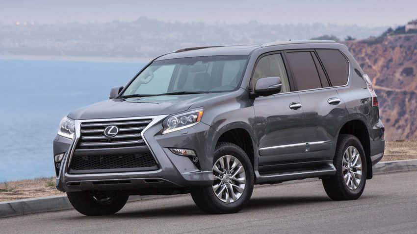 A gray lexus suv is driving down the street.