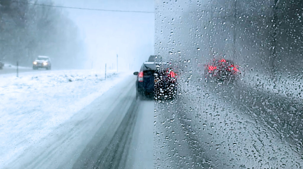 A car driving on the road in heavy snow.